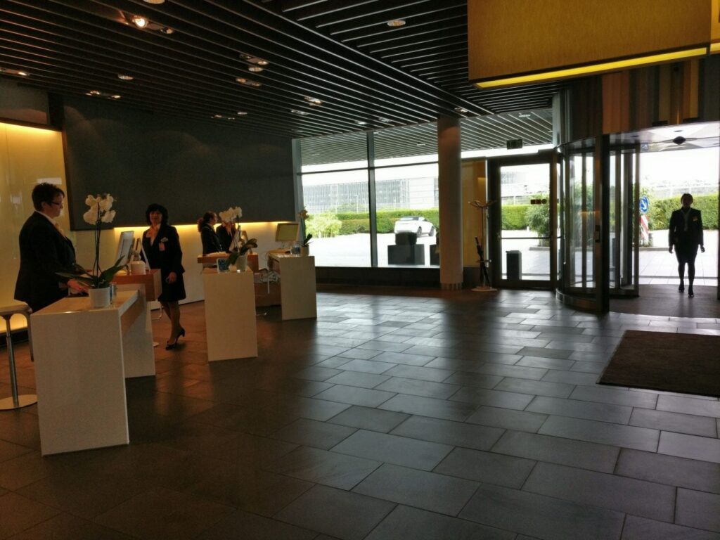 a lobby with a glass door and a woman standing in front of it