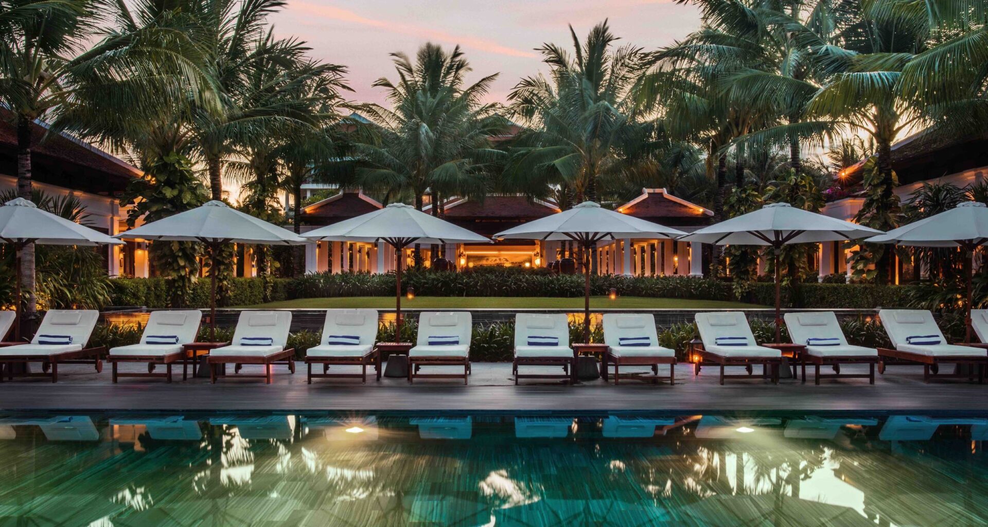 a pool with chairs and umbrellas in front of a building