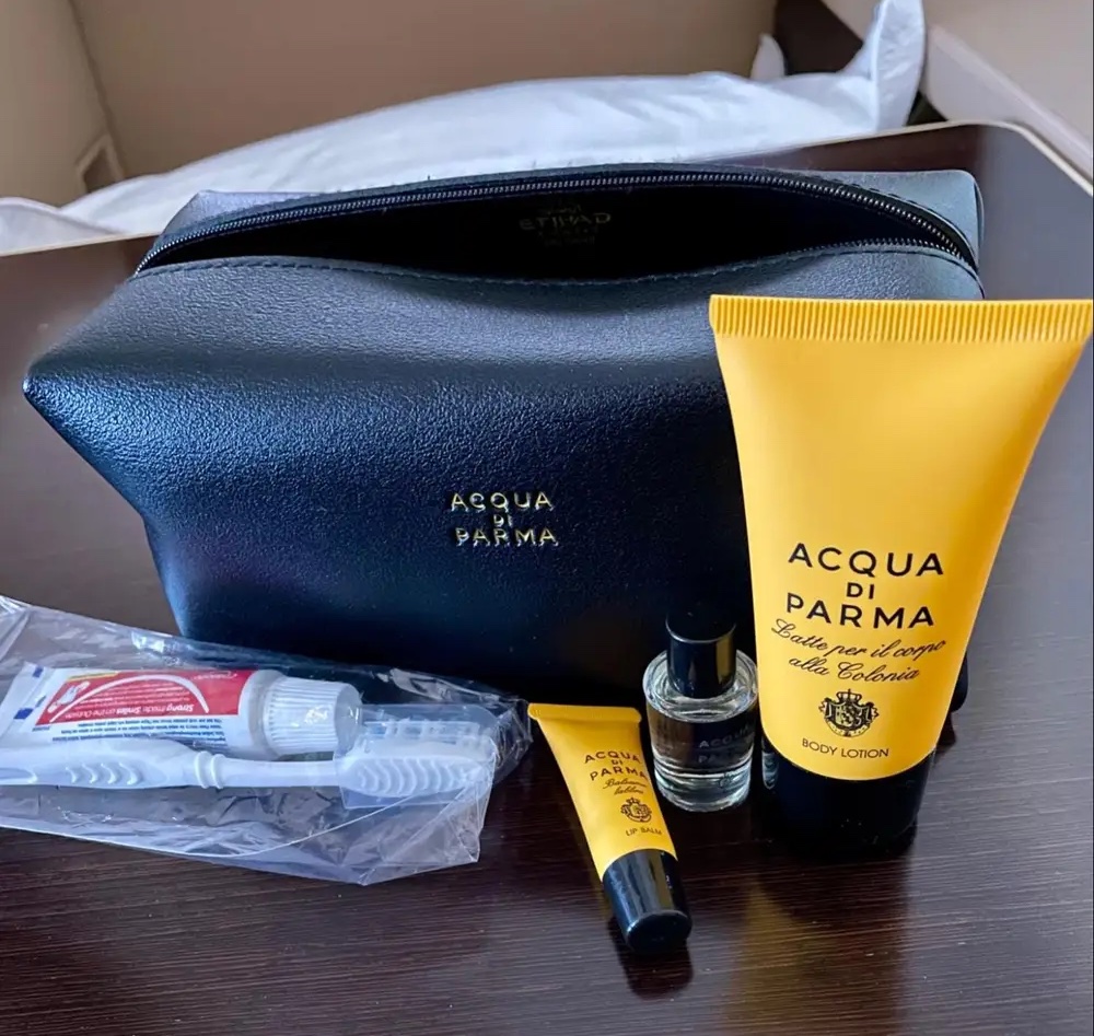 a black bag with a small yellow tube and small bottles of cosmetics on a table