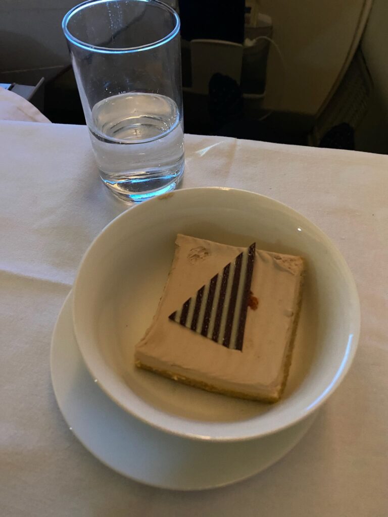 a piece of cake in a bowl next to a glass of water