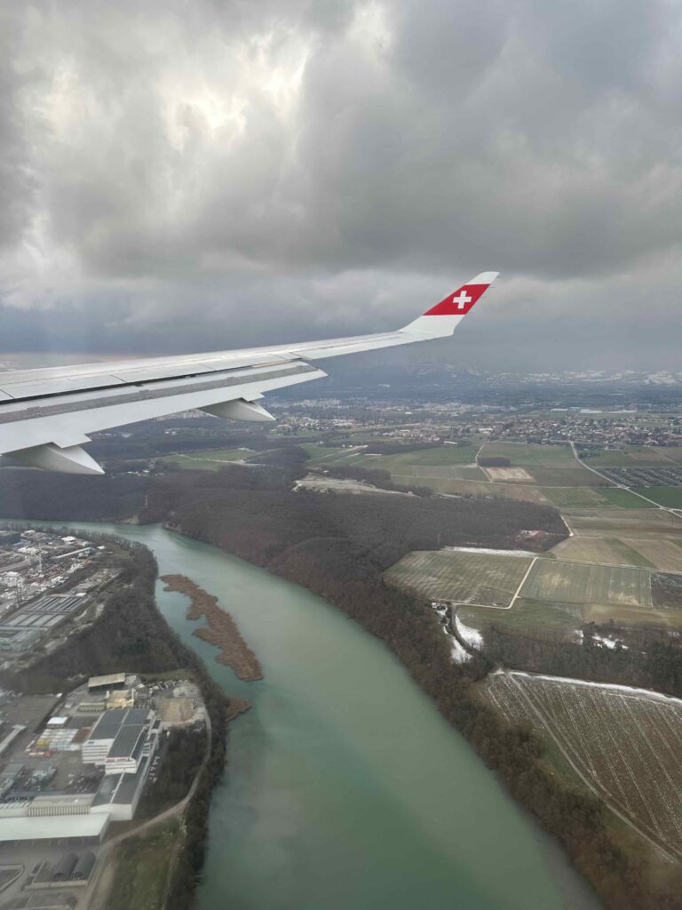 an airplane wing with a red cross on the tail and a river in the background