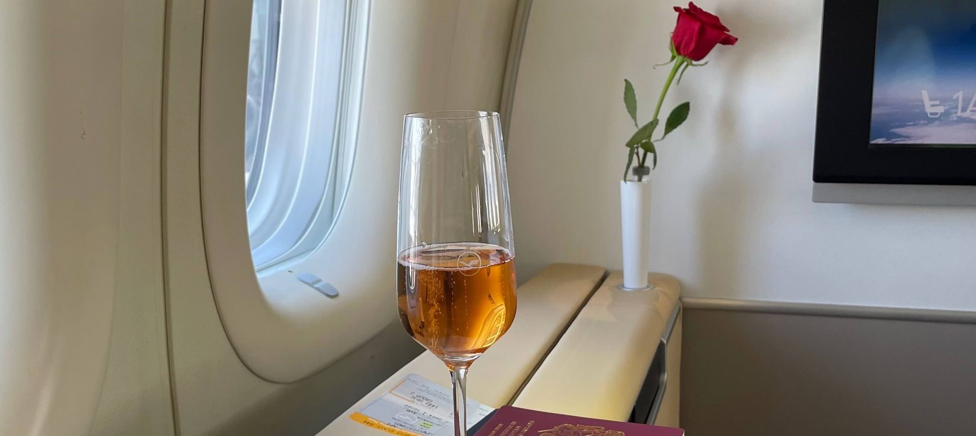 a glass of wine on a table with a rose in the background