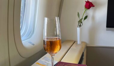 a glass of wine on a table with a rose in the background