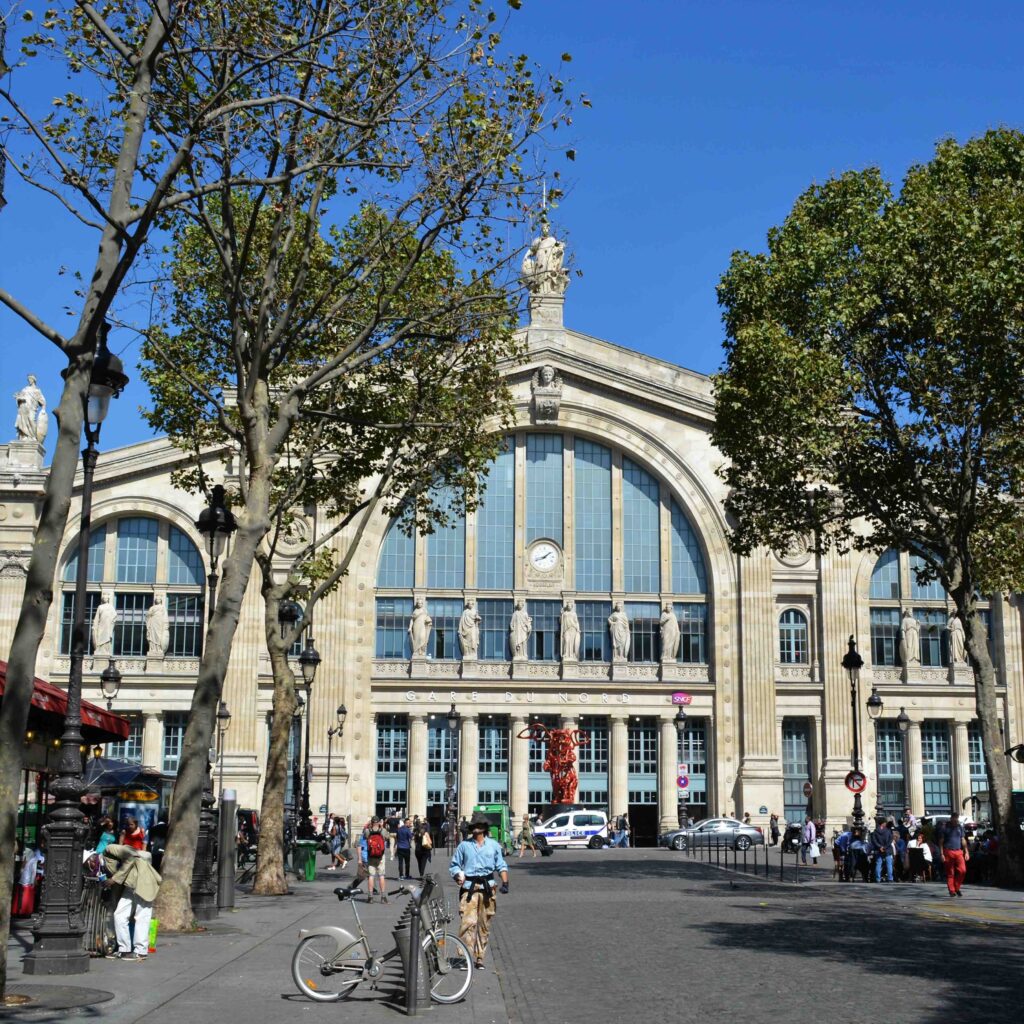 a large building with trees and people walking on a sidewalk