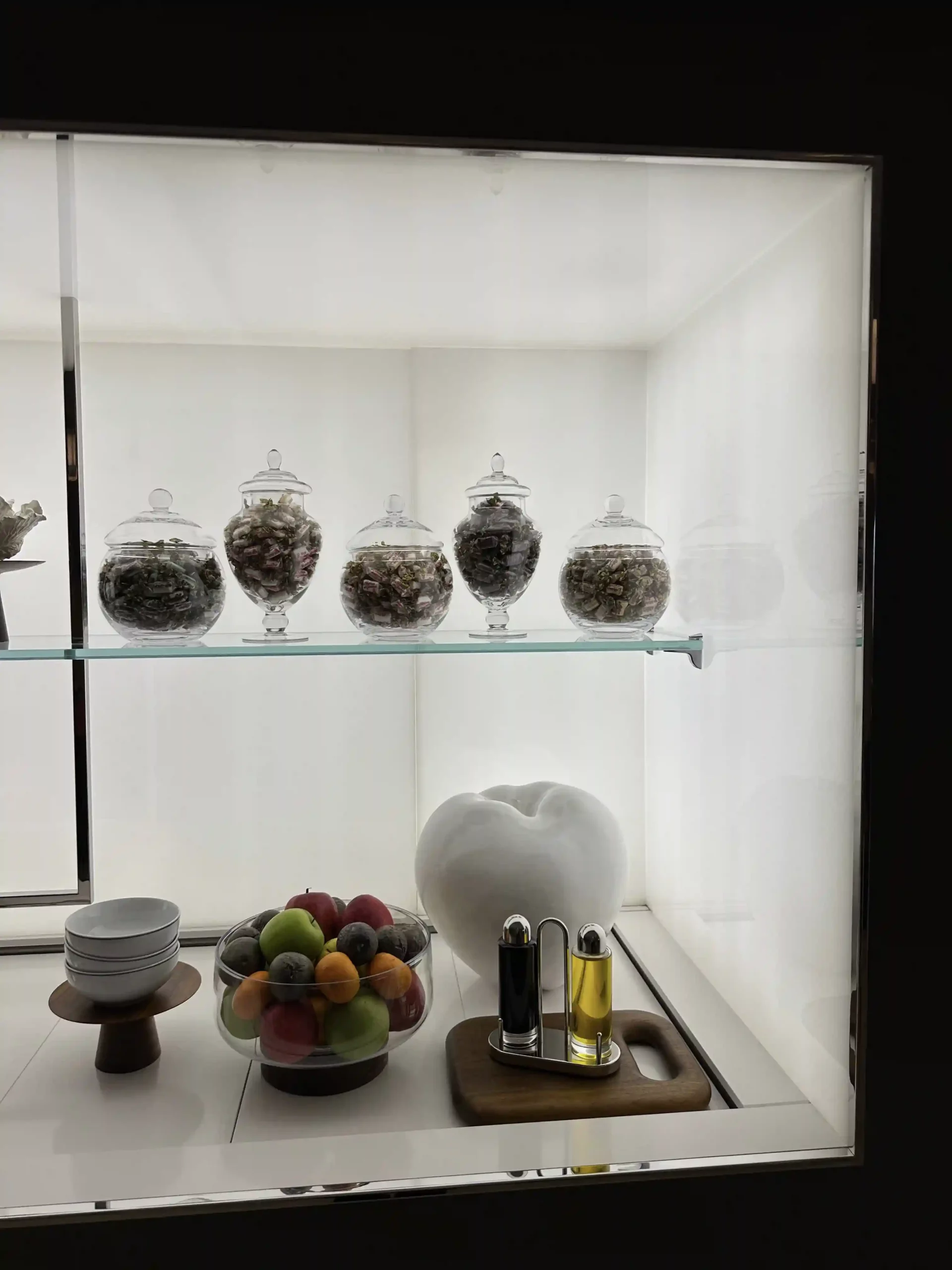 a glass shelf with bowls and fruit on it