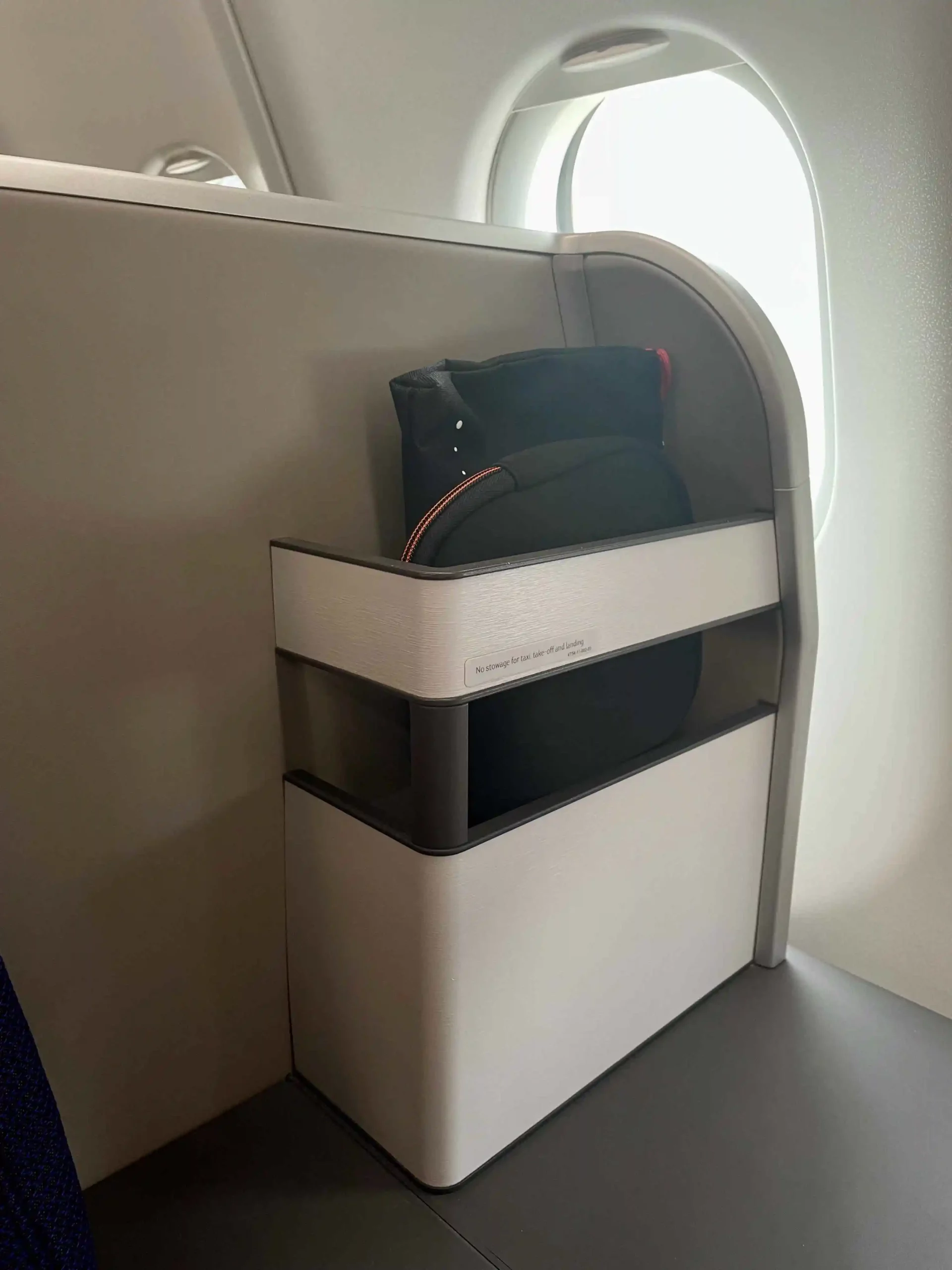 a black bag in a white shelf on a plane