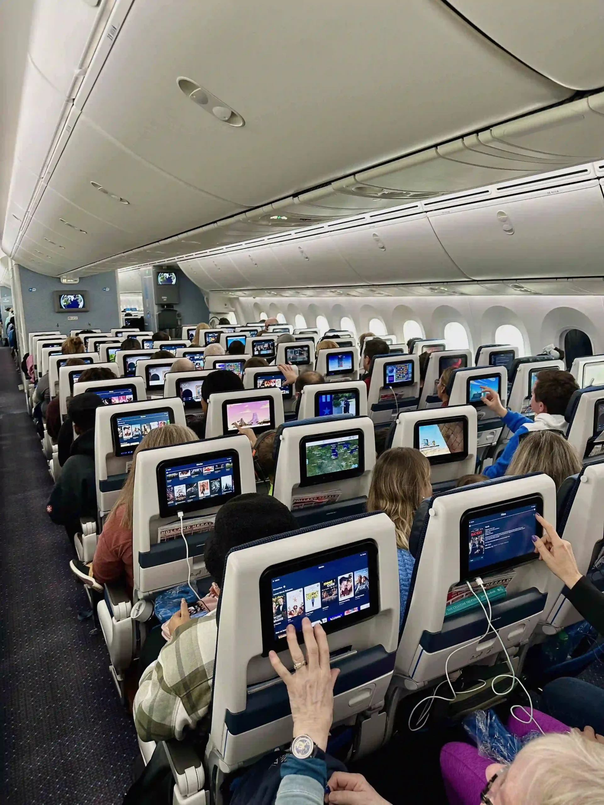 a group of people sitting in an airplane with a screen on the back