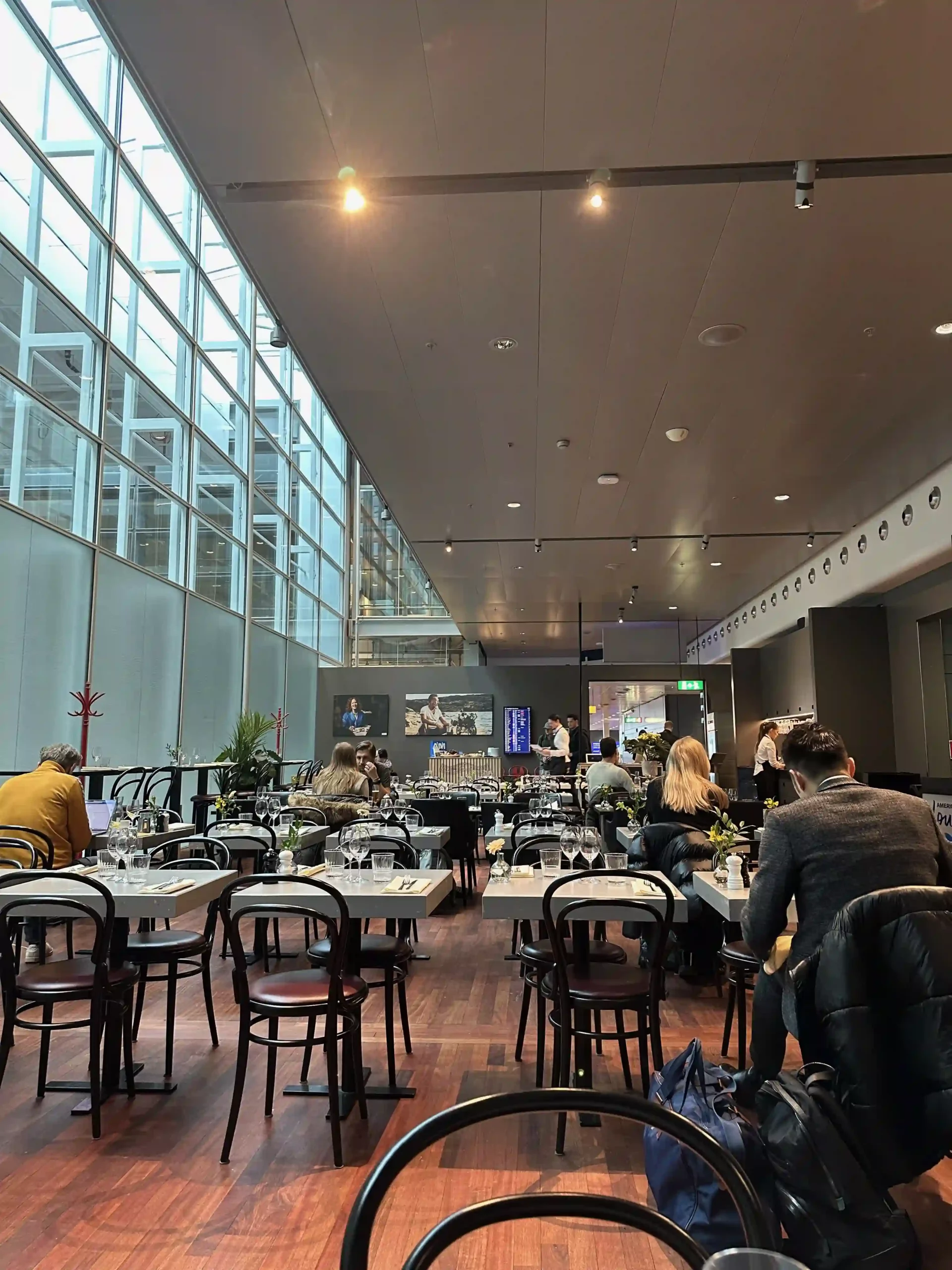 a group of people sitting at tables in a room with windows