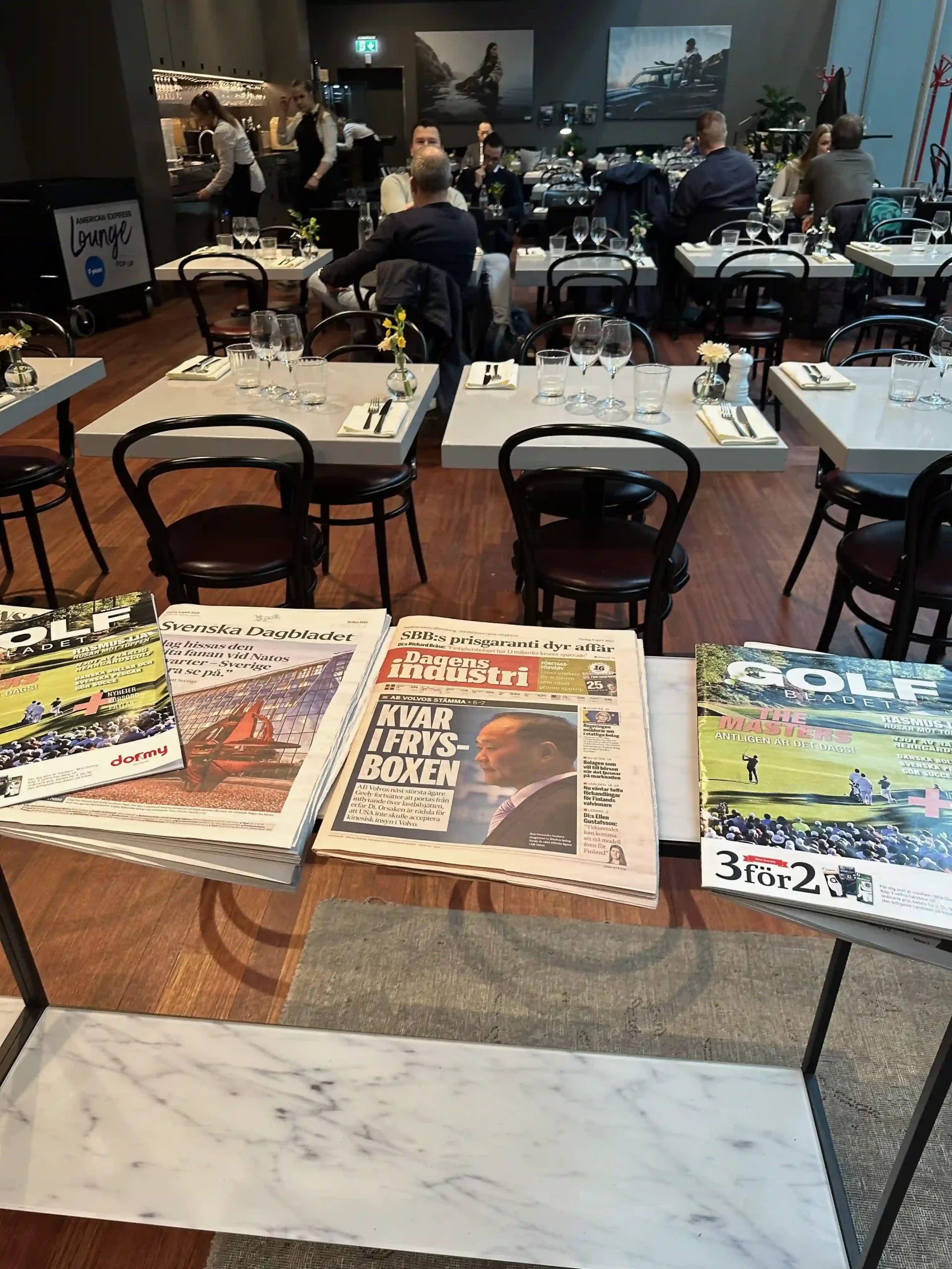 a group of people sitting at tables with magazines and glasses
