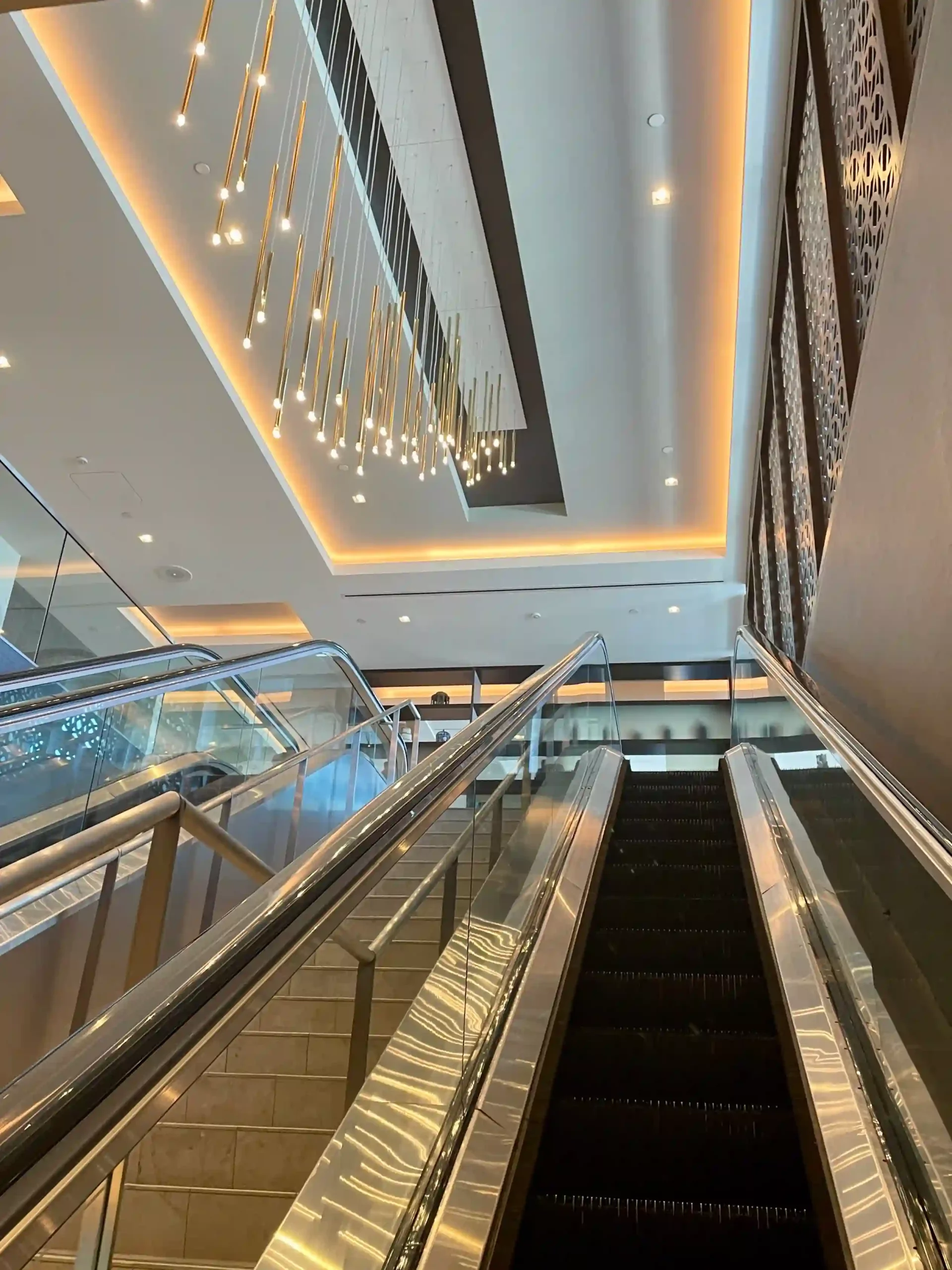 escalators in a building with a chandelier from the ceiling