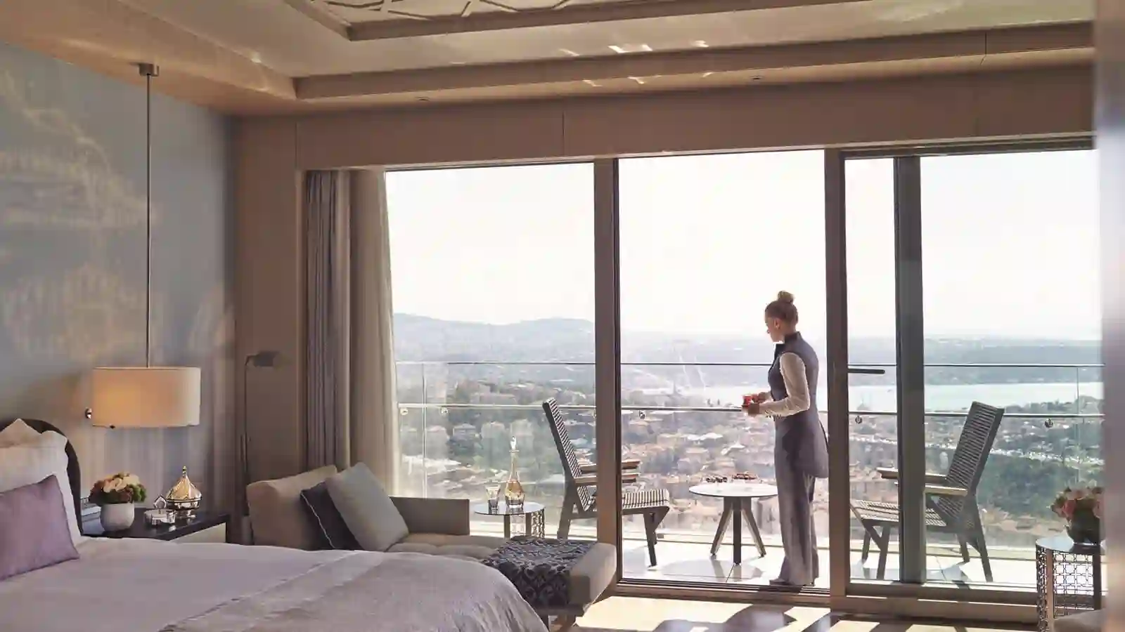 a woman standing in a hotel room looking out the window