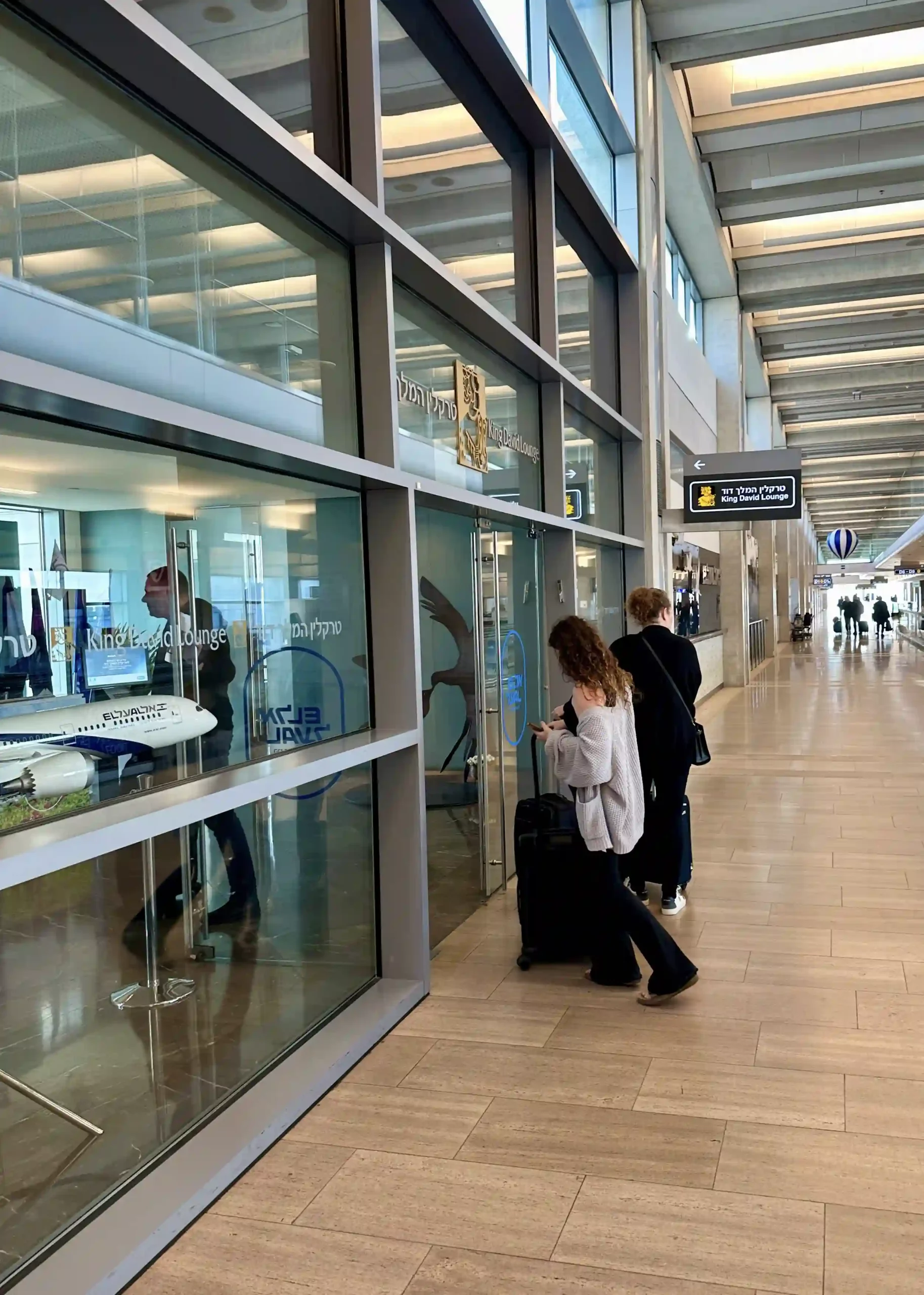 people standing in a hallway with a glass wall and a couple of people