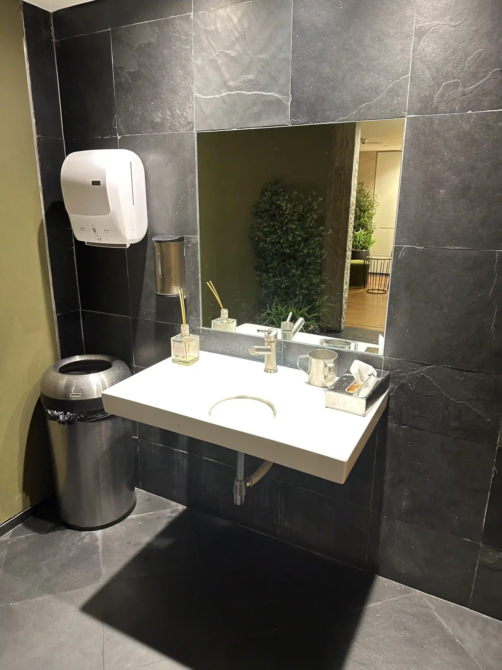 a bathroom sink with a mirror and a trash can