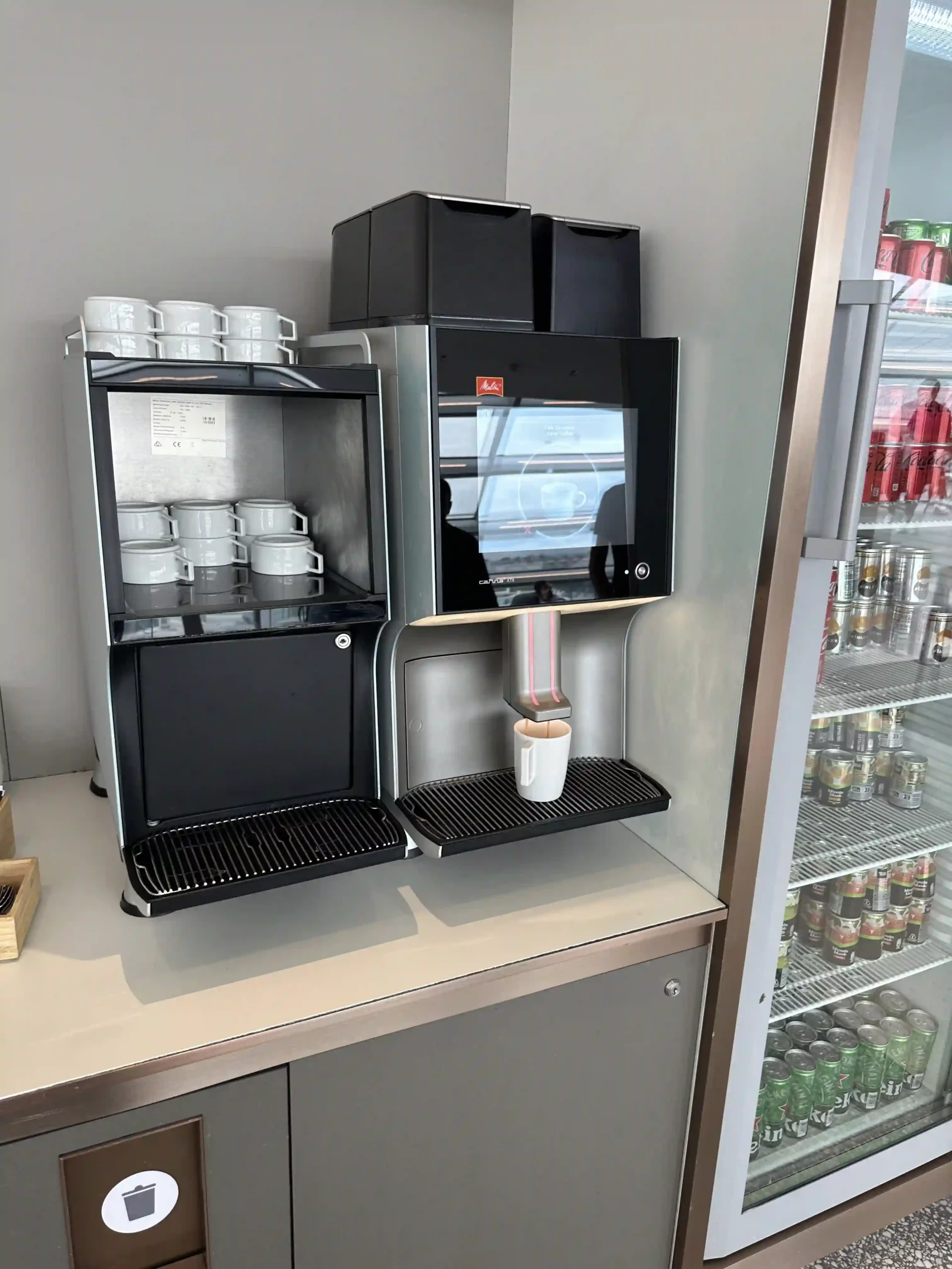 a coffee machine with cups on the shelf