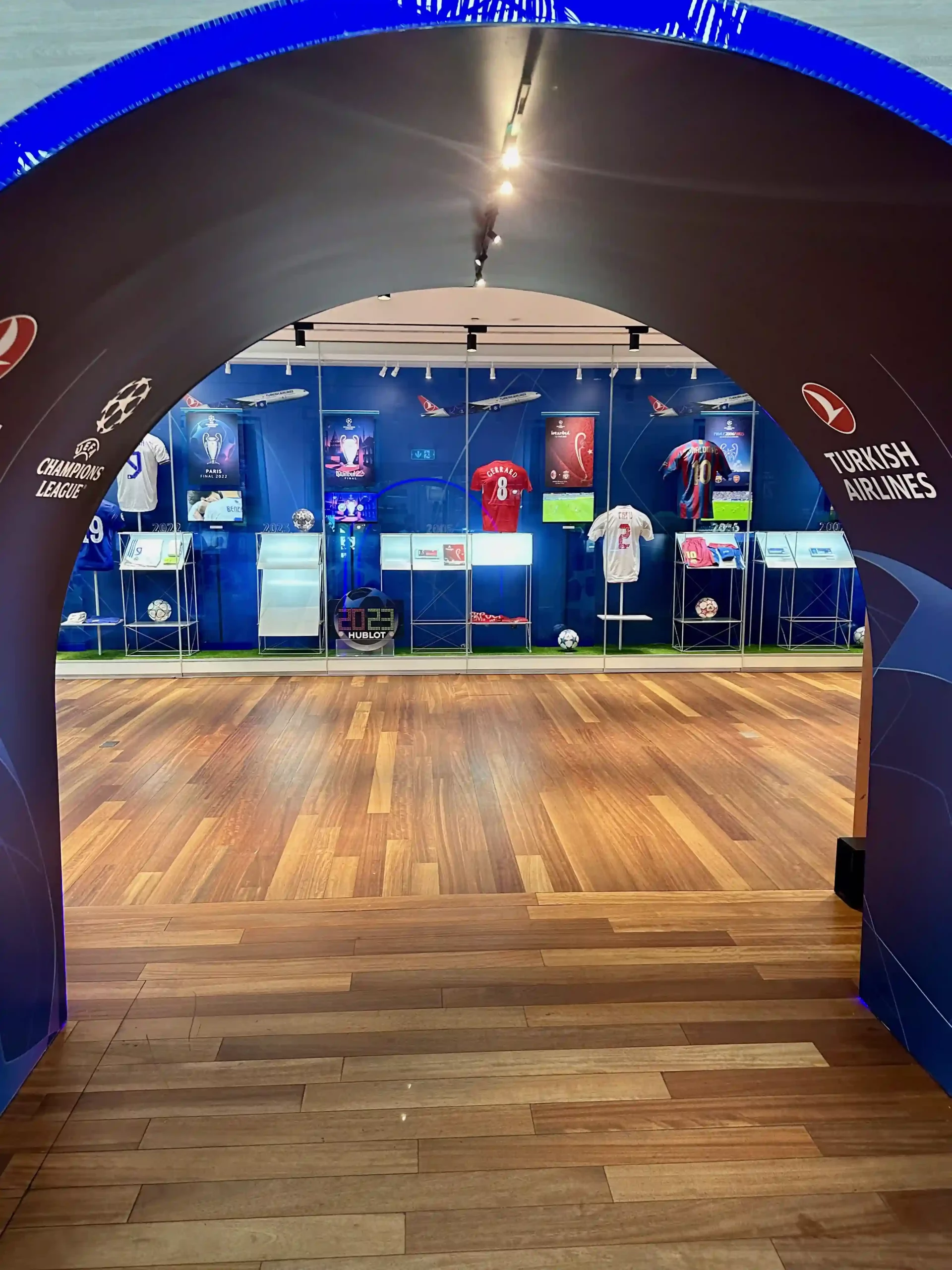 a room with a wood floor and a wood floor with a wood floor and a blue wall with signs and sports items on it