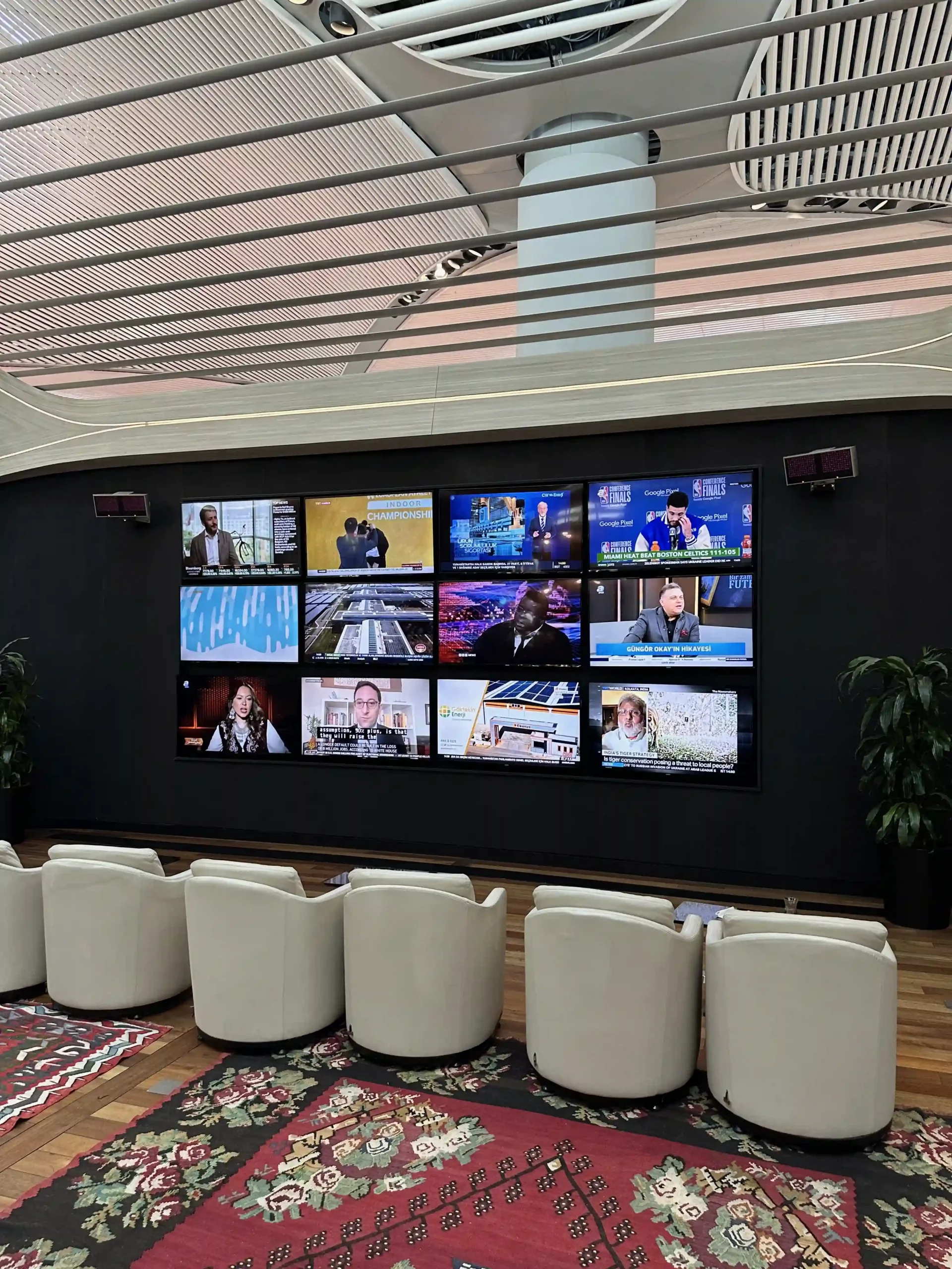 a room with white chairs and a large wall with many screens