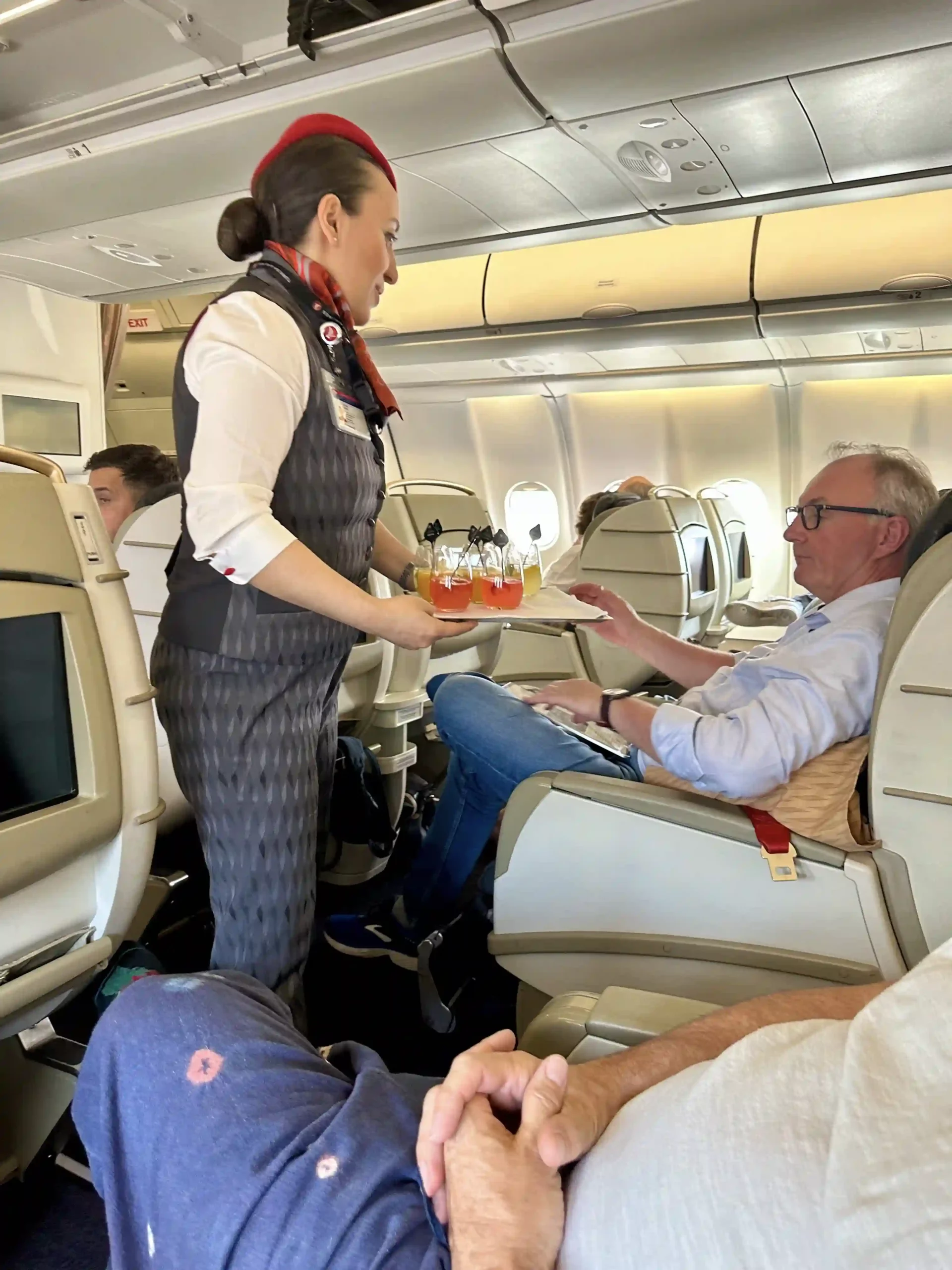 a woman serving drinks on a tray in an airplane