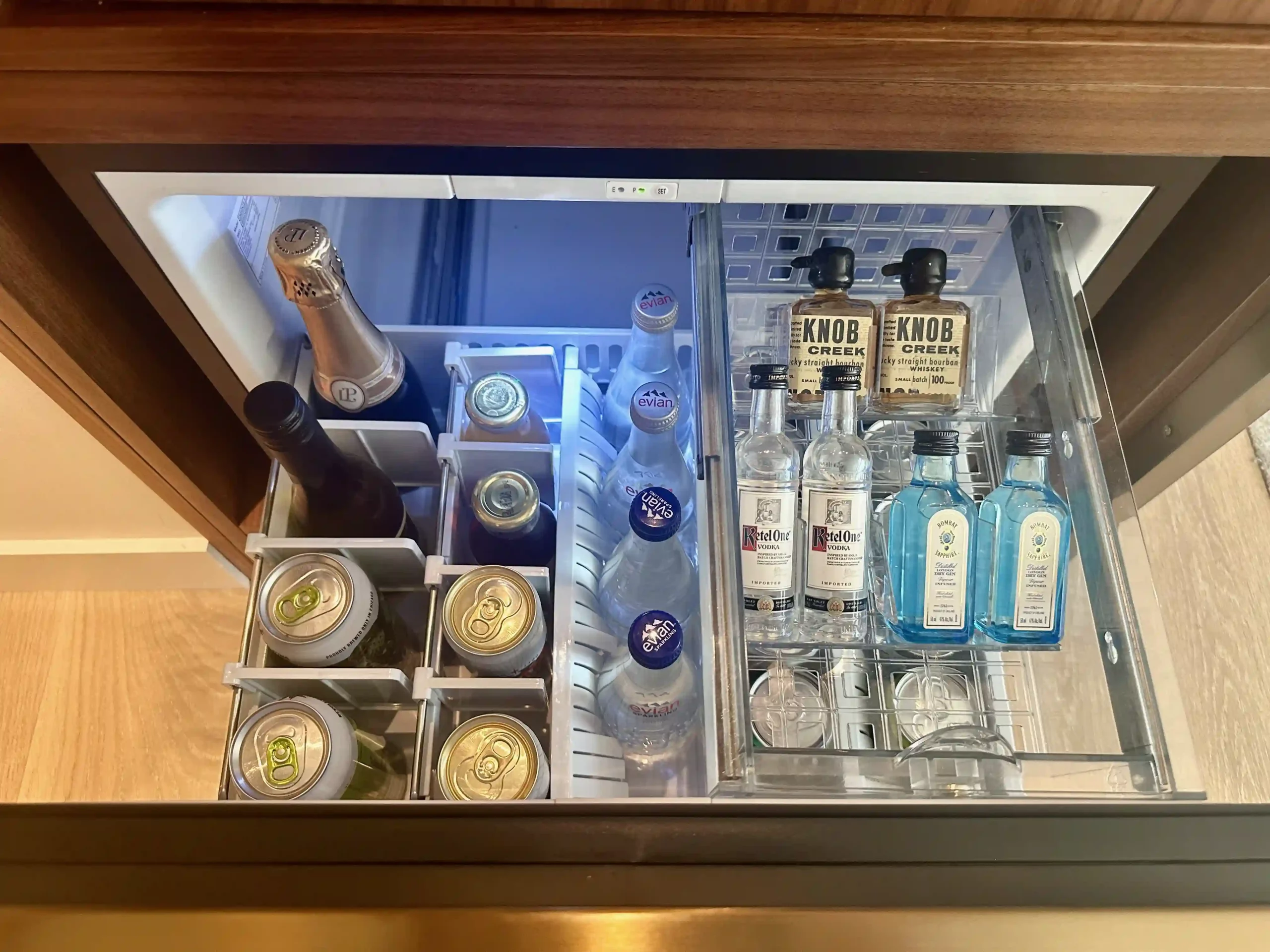 a mini fridge with bottles and glasses