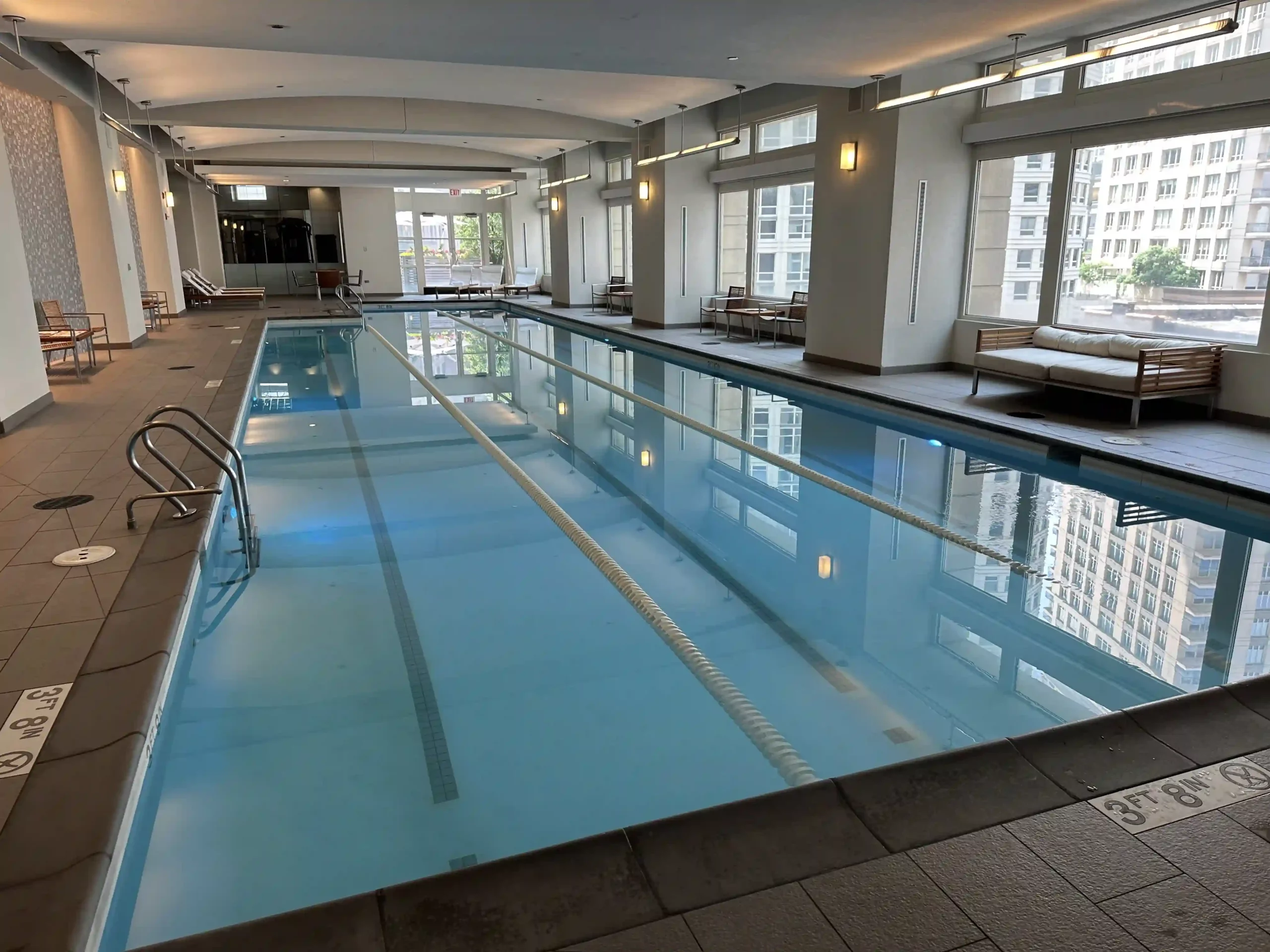 a indoor swimming pool with a large white wall and windows