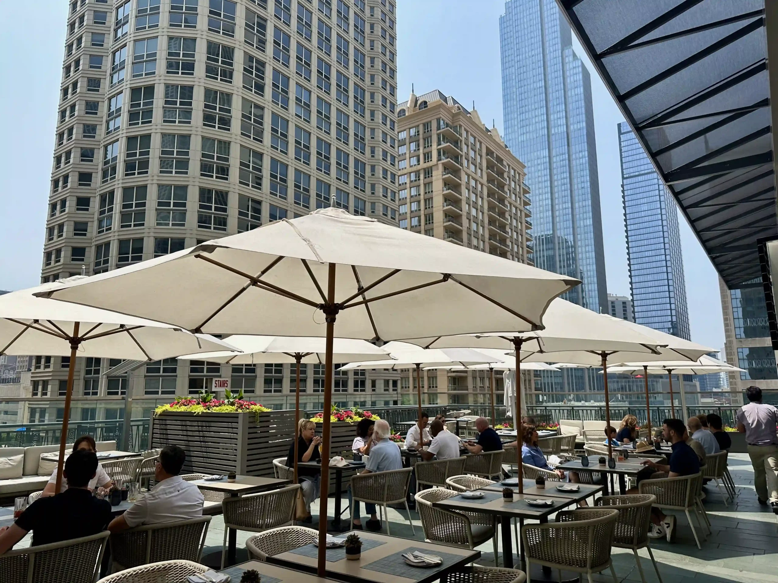 a group of people sitting at tables with umbrellas in a city