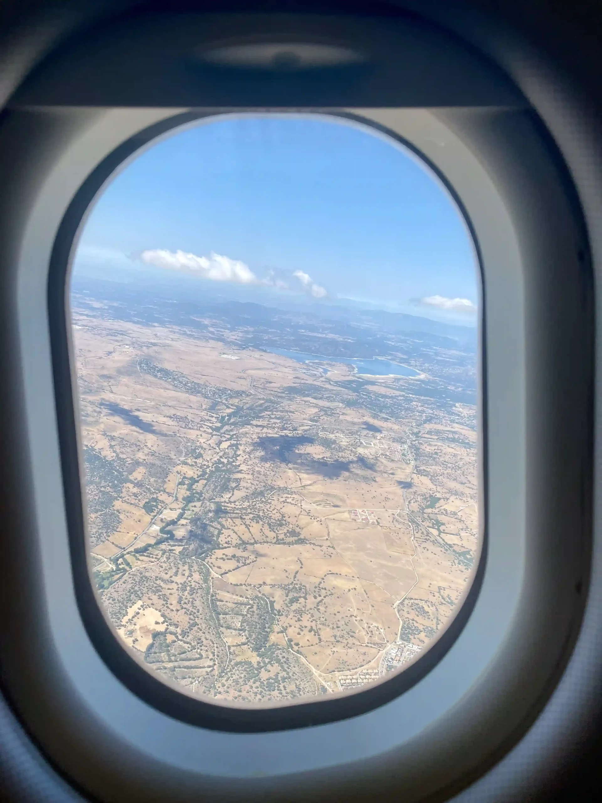 an airplane window with a view of land and a lake