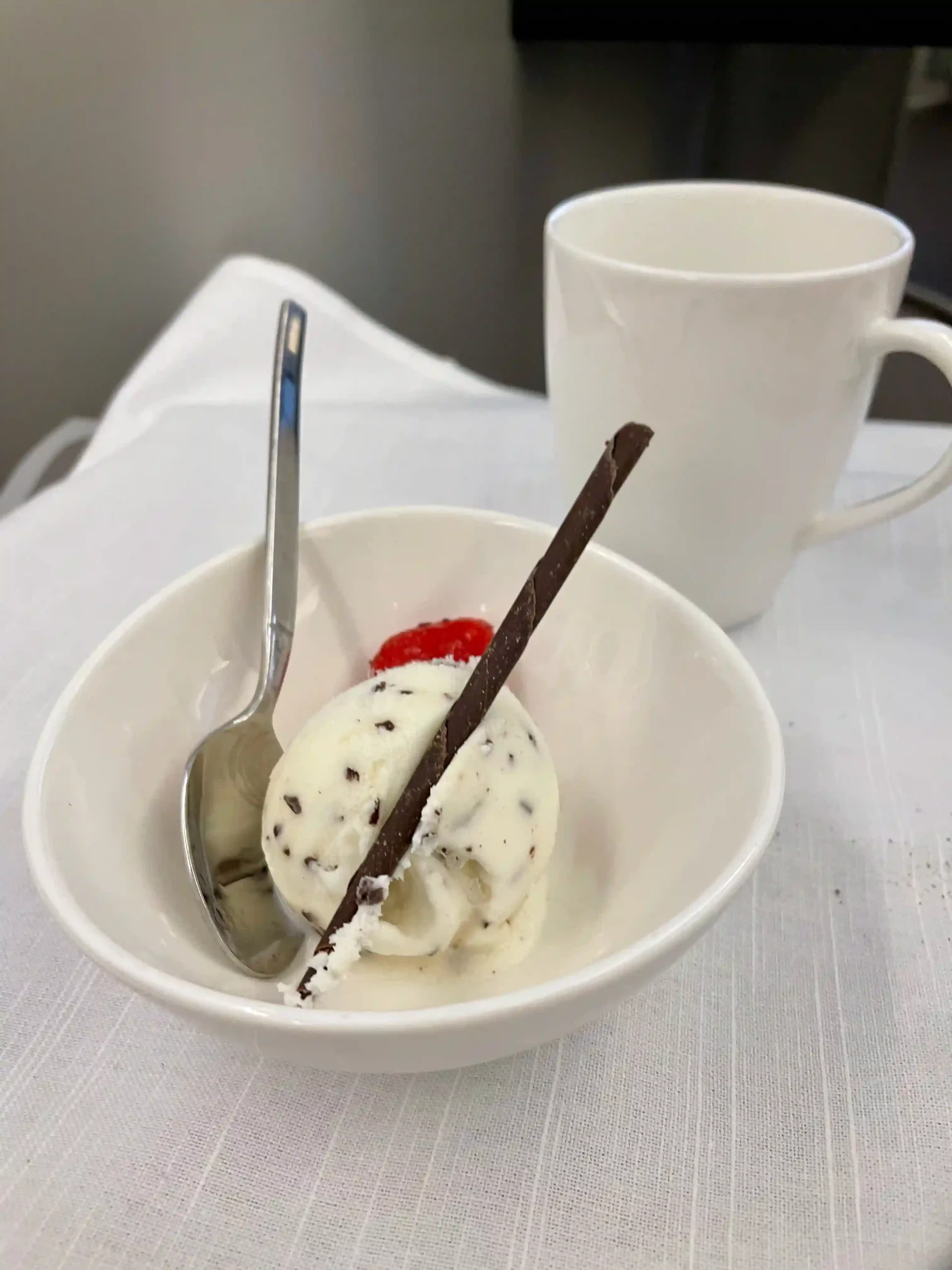 a bowl of ice cream with a spoon and a cup of coffee