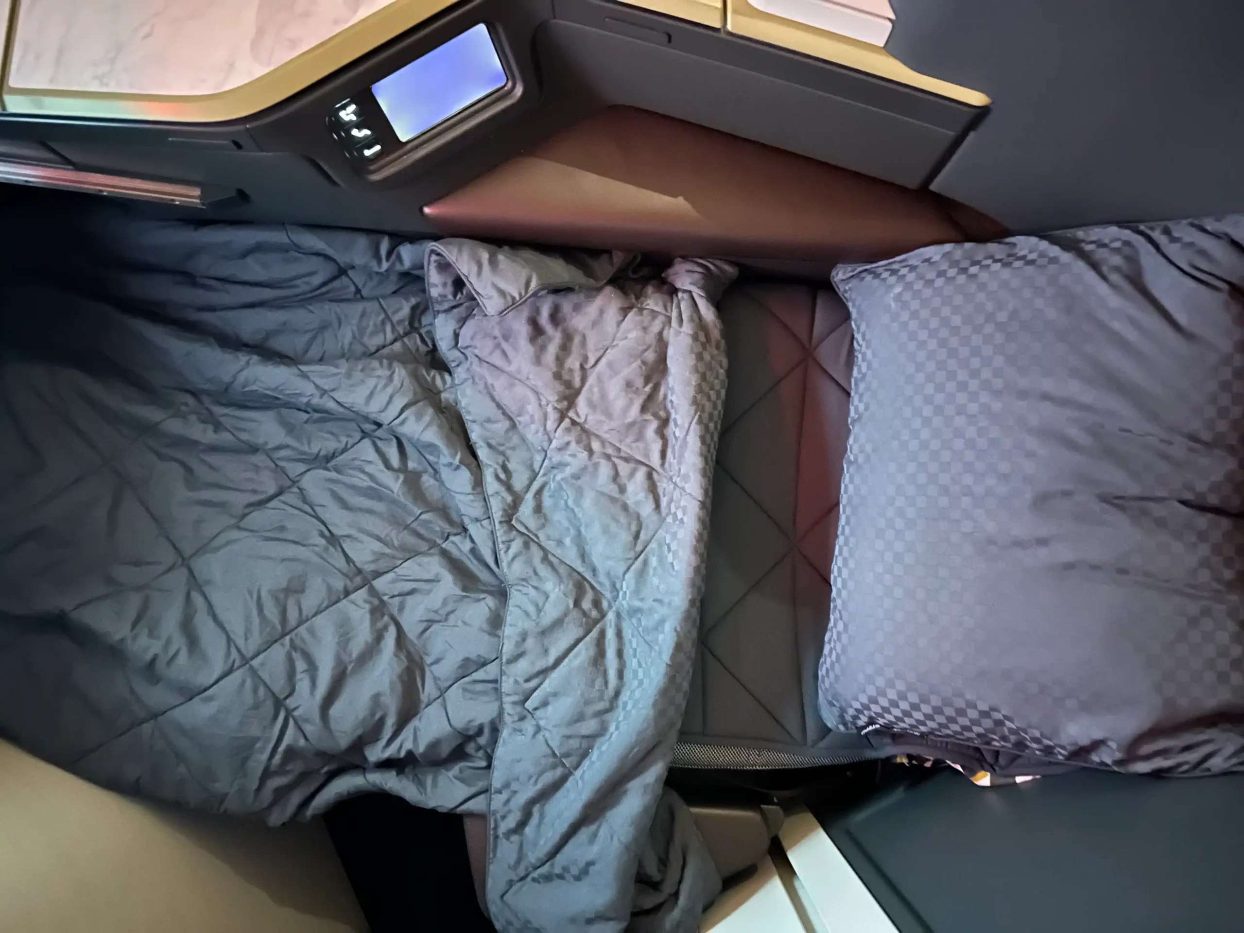 a bed with a blanket and pillows on a plane